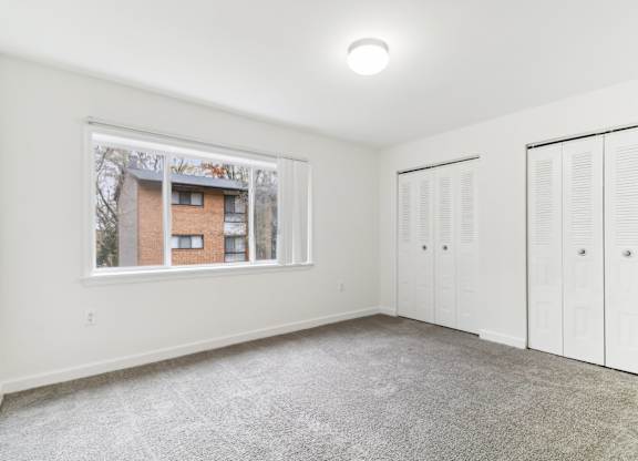a room with two closets and a window and a carpeted floor at Oaks at Oxon Hill, Oxon Hill, Maryland
