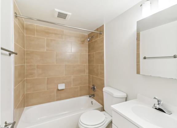 a bathroom with a toilet sink and tub and a mirror at Oaks at Oxon Hill, Oxon Hill, Maryland