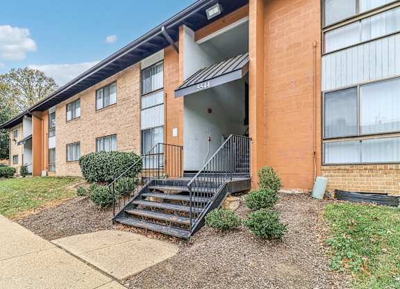 an apartment building with stairs and a sidewalk in front of it at Oaks at Oxon Hill, Oxon Hill, Maryland