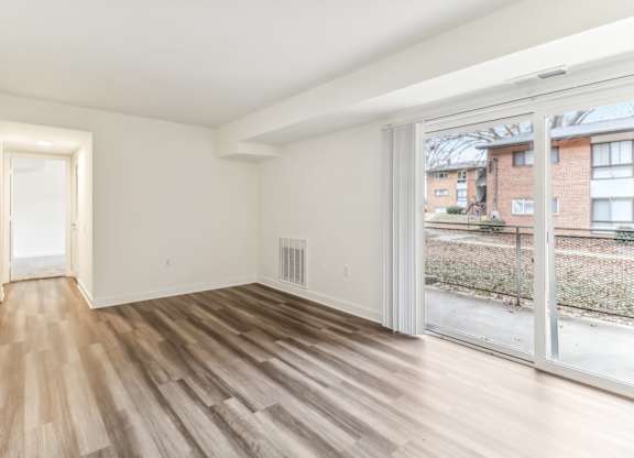 an empty living room with wood flooring and a large window at Oaks at Oxon Hill, Oxon Hill, Maryland