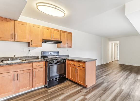a kitchen with wooden cabinets and a stove and a sink at Oaks at Oxon Hill, Oxon Hill, Maryland