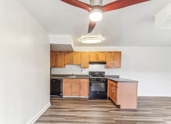 a kitchen with wooden cabinets and black appliances and a ceiling fan at Oaks at Oxon Hill, Oxon Hill, Maryland