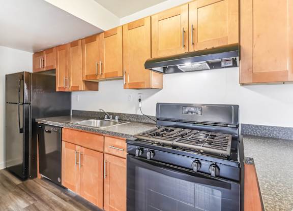 a kitchen with black appliances and wooden cabinets at Oaks at Oxon Hill, Oxon Hill, Maryland