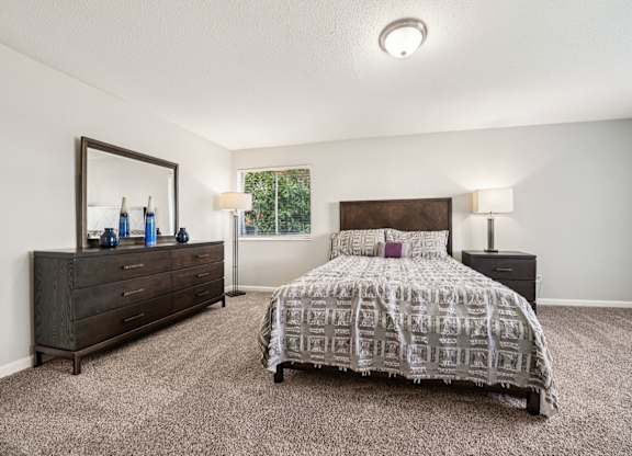 A bedroom with a bed, dresser, and mirror.