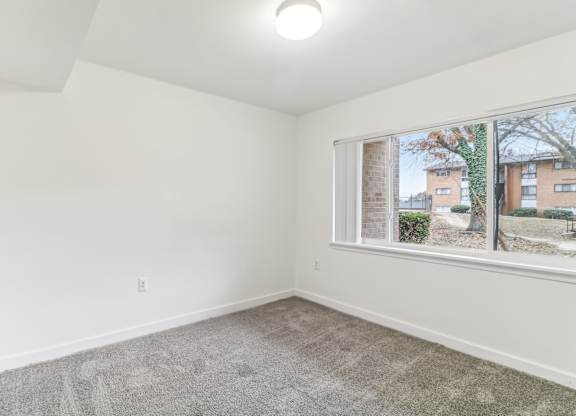 an empty living room with a large window and carpet at Oaks at Oxon Hill, Oxon Hill, Maryland