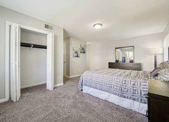 A bedroom with a bed, dresser, and mirror.