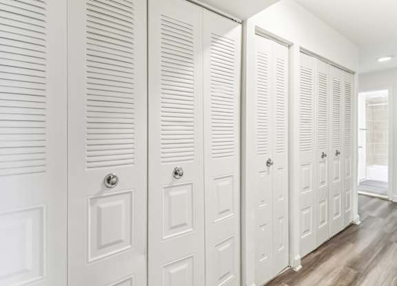 a row of white closet doors in a room with wood floors at Oaks at Oxon Hill, Oxon Hill, Maryland