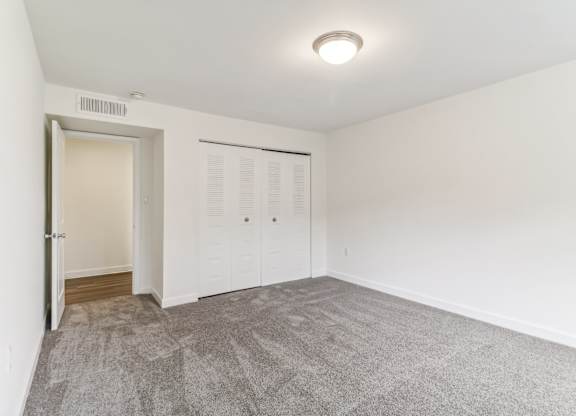 a living room with carpet and a door to a closet at Oaks at Oxon Hill, Oxon Hill, Maryland