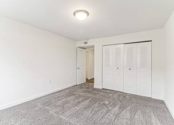 a bedroom with white walls and a door to a closet at Oaks at Oxon Hill, Oxon Hill, Maryland