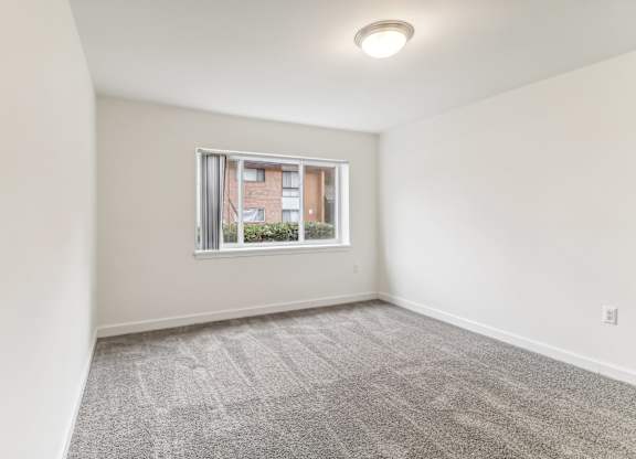 an empty living room with a window and white walls at Oaks at Oxon Hill, Oxon Hill, Maryland