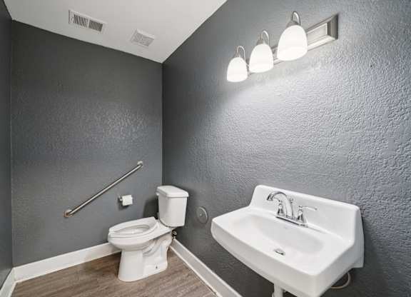 A bathroom with a toilet, sink, and lights.