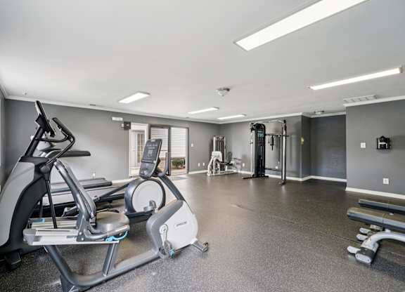 A spacious gym with a treadmill, elliptical trainer, and other exercise equipment.