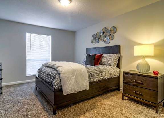 A bedroom with a bed, nightstand, and lamp at The Onyx Hoover Apartments, Hoover