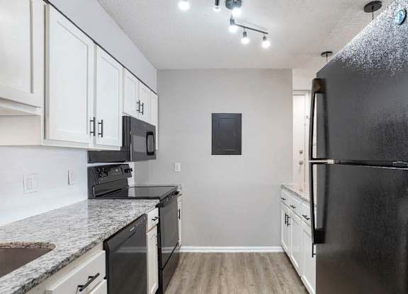 A black refrigerator is on the right side of a kitchen at The Onyx Hoover Apartments, Hoover, AL