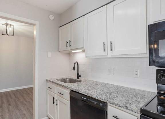 A kitchen with white cabinets and a granite countertop at The Onyx Hoover Apartments, Alabama, 35216
