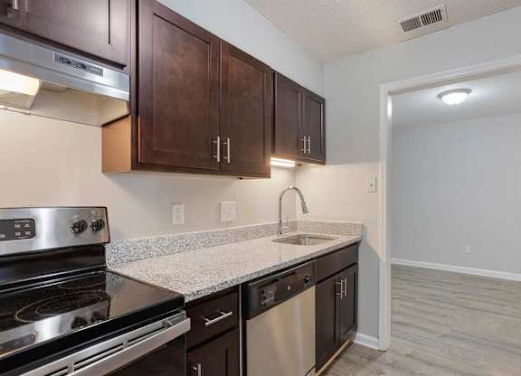 A kitchen with dark brown cabinets and stainless steel appliances at The Onyx Hoover Apartments, Hoover, Alabama
