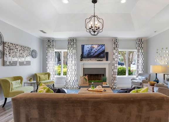 A living room with a brown couch and a chandelier at The Onyx Hoover Apartments, Hoover