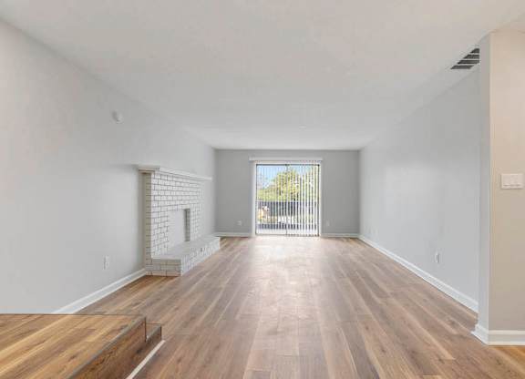 A spacious room with wooden flooring and a brick fireplace. at The Onyx Hoover Apartments, Alabama, 35216