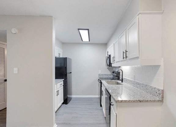 A kitchen with white cabinets and a black refrigerator at The Onyx Hoover Apartments, Alabama