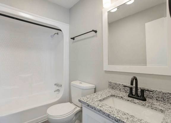 A white toilet sits next to a sink in a bathroom at The Onyx Hoover Apartments, Hoover, AL