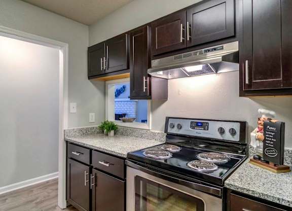 A kitchen with a stove top oven and a microwave. at The Onyx Hoover Apartments, Hoover, 35216