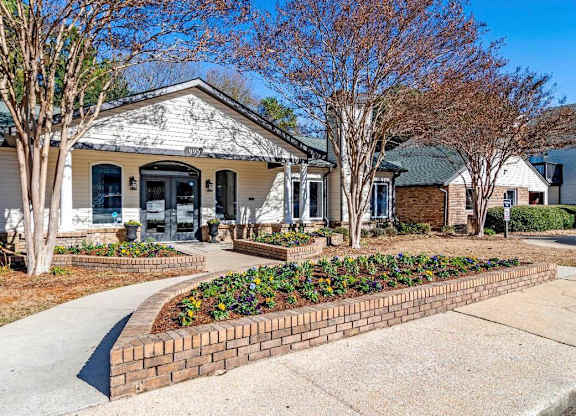 A white house with a brick flower bed in front at The Onyx Hoover Apartments, Hoover, AL, 35216