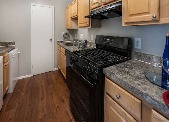 a kitchen with wooden cabinets and a black stove top oven at The Glendale Residence, Maryland