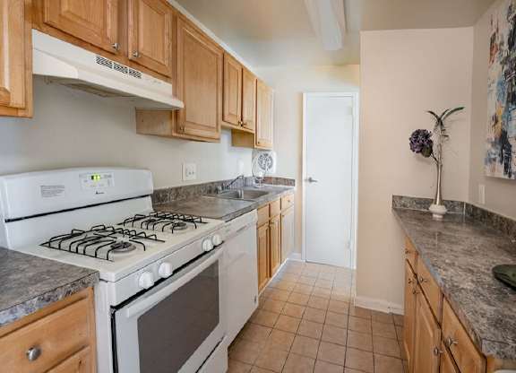 a kitchen with wooden cabinets and a white stove top oven at The Glendale Residence, Lanham, MD