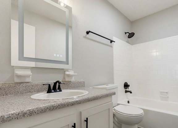 A white bathroom with a sink, toilet, and bathtub at The Onyx Hoover Apartments, Hoover, 35216