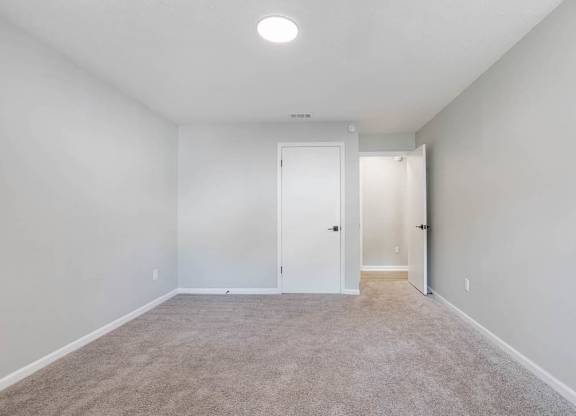 A room with a carpeted floor and a white door at The Onyx Hoover Apartments, Alabama, 35216