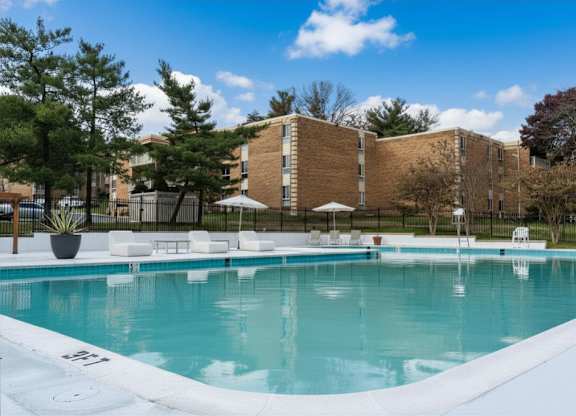 A swimming pool in front of a brick building with trees in the background.