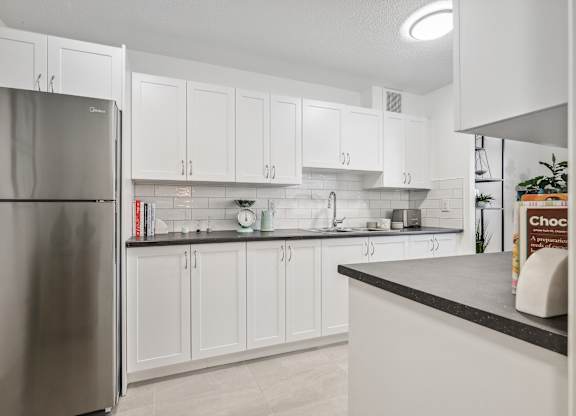 an open kitchen with white cabinets and a stainless steel refrigerator