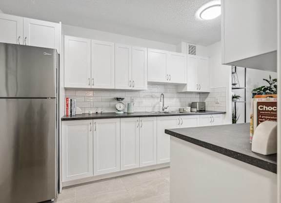 a large kitchen with white cabinets and a stainless steel refrigerator