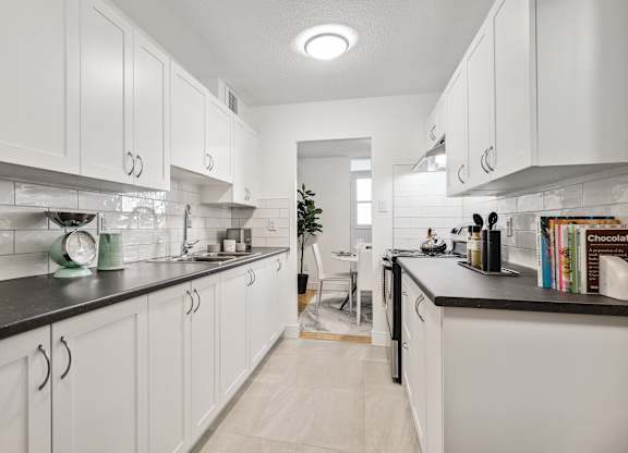 a white kitchen with white cabinets and black counter tops