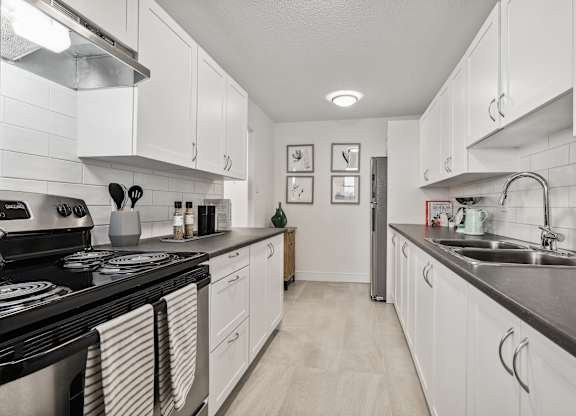 a kitchen with white cabinets and black counter tops and a sink