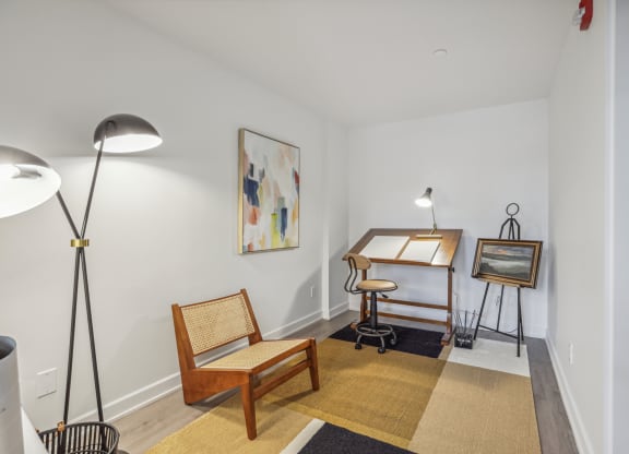 a living room with a desk and chair and a painting on the wall