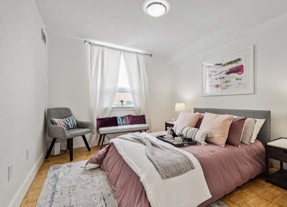 a bedroom with a bed and two chairs and a window