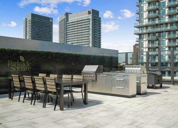 a communal terrace with a table and barbecue grill on a rooftop