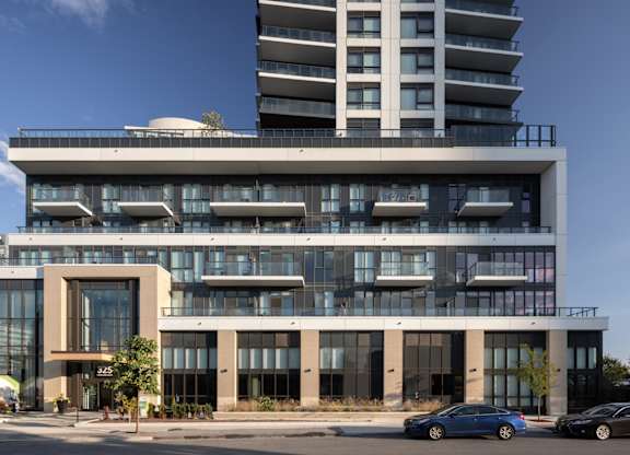 A modern building with a glass facade and a car parked in front.