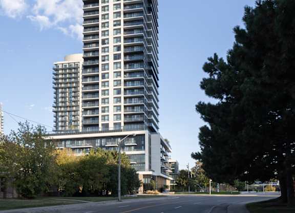 A tall building with many windows stands next to a tree.