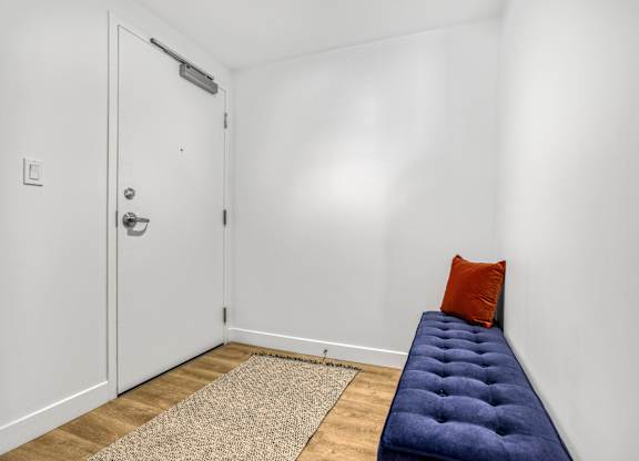 A room with a door, a pillow, and a bench.