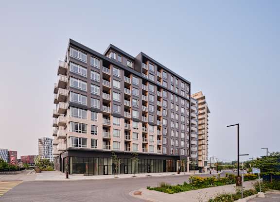 A modern multi-story building with a parking lot in front.