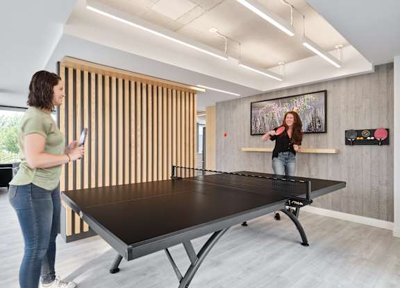 A woman is playing ping pong in a room with a wooden wall.