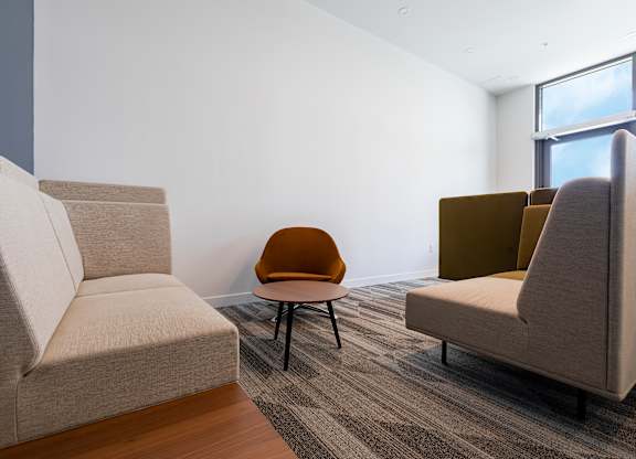 A room with a grey sofa, a brown chair and a grey chair.