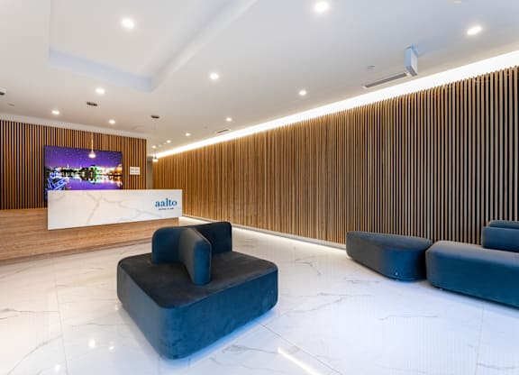 A modern waiting area with a wooden wall and a white reception desk.