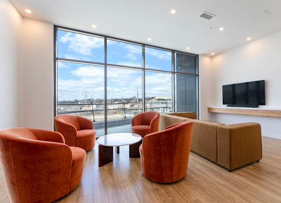 A living room with orange chairs and a flat screen TV.
