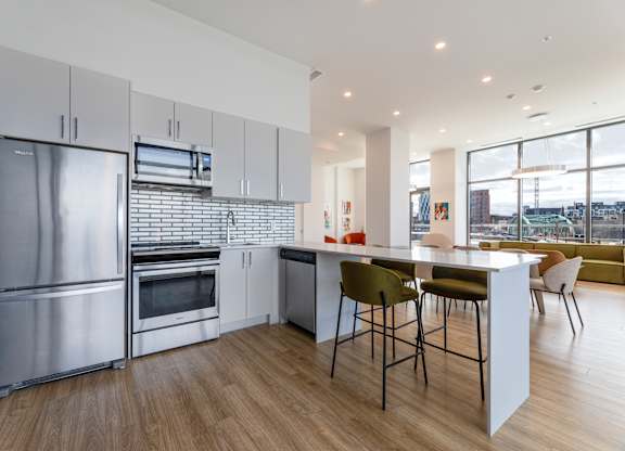 A modern kitchen with stainless steel appliances and wooden flooring.