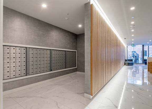 A long hallway with a marble floor and a wooden wall on the right side.