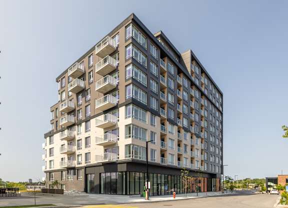A modern multi-story residential building with balconies and a black entrance.