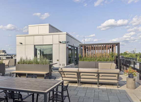 a roof deck with patio furniture and a building in the background